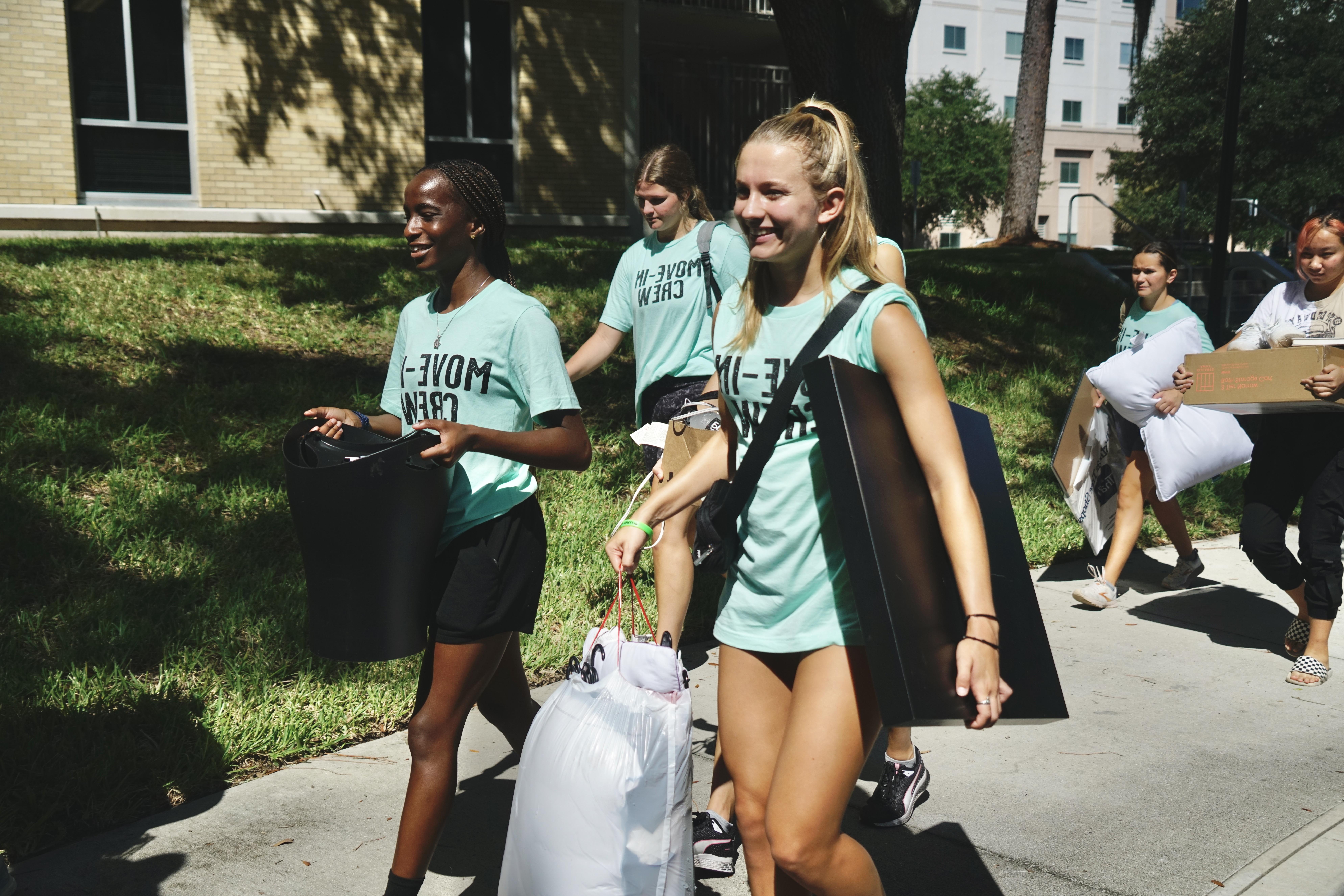  Smiling students help carry items inside during move-in.